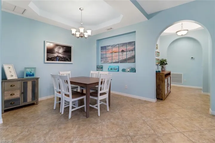 Dining area featuring a notable chandelier, light tile patterned floors, and a tray ceiling