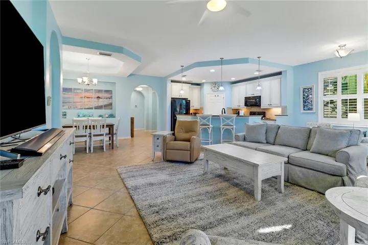 Living room featuring ceiling fan with notable chandelier and light tile patterned floors