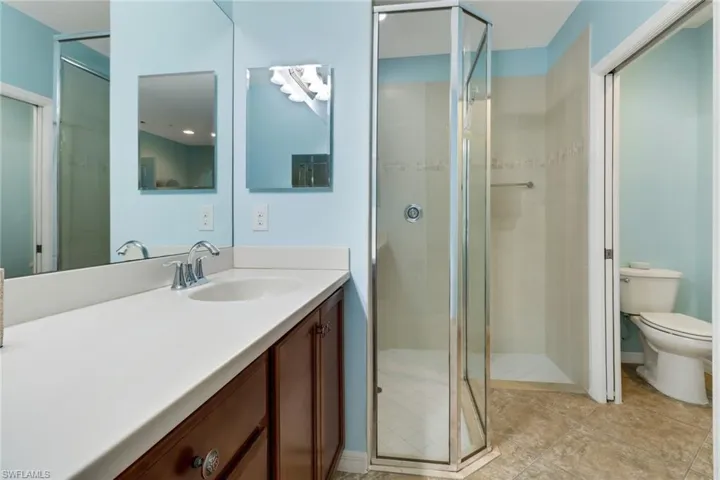 Bathroom featuring vanity, toilet, and a shower with door