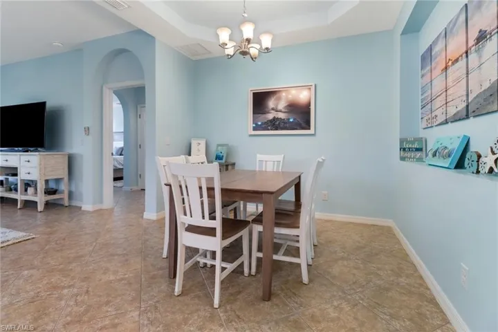 Dining area with a tray ceiling, a chandelier, and light tile patterned flooring