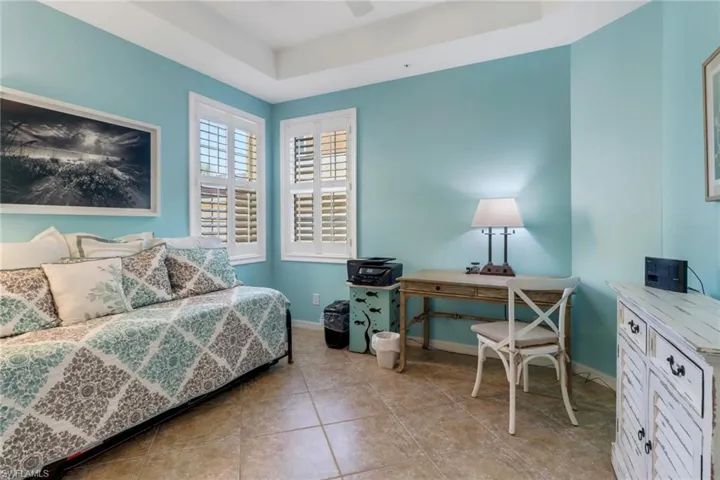 Bedroom with a tray ceiling, light tile patterned floors, and ceiling fan