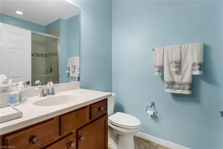 Bathroom with vanity, toilet, tile patterned flooring, and a shower with door
