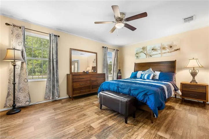 Bedroom with multiple windows, ceiling fan, and light hardwood / wood-style flooring