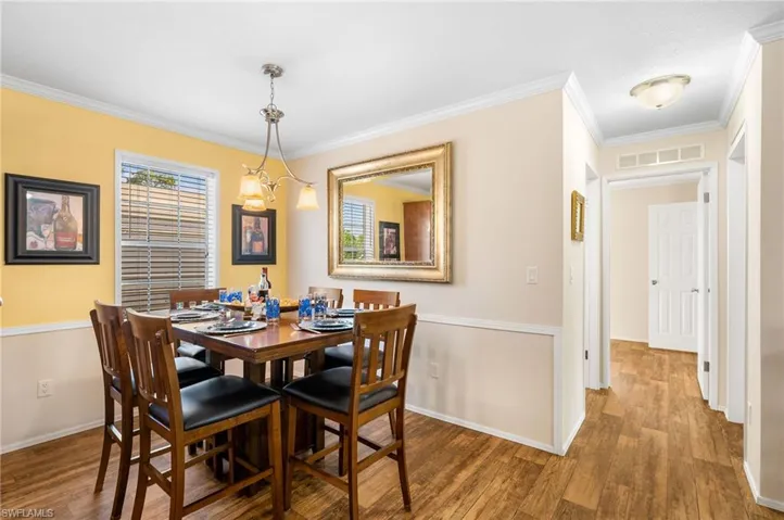 Dining space with dark hardwood / wood-style flooring, a notable chandelier, and ornamental molding
