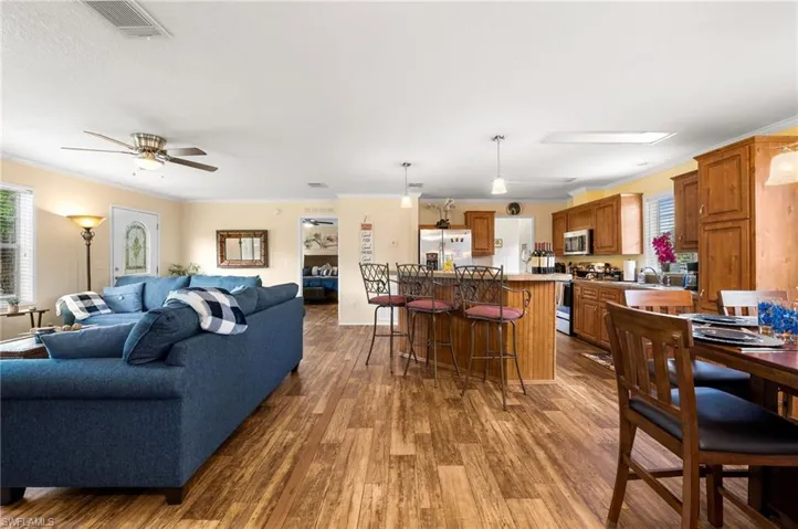 Living room featuring ceiling fan, hardwood / wood-style flooring, crown molding, and sink
