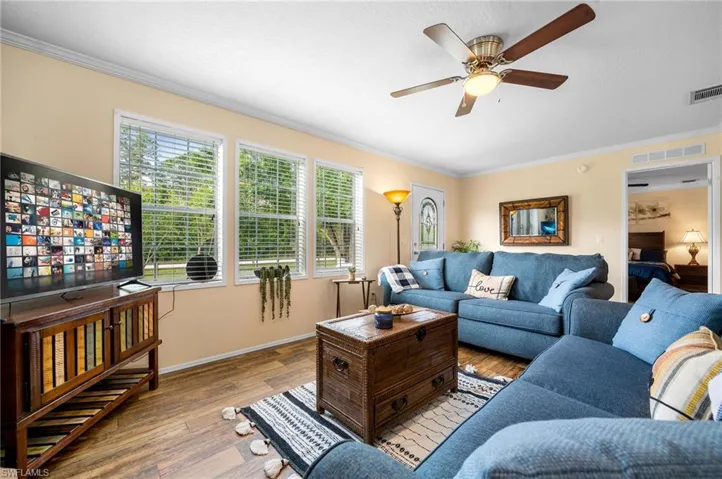 Living room with crown molding, ceiling fan, and light hardwood / wood-style floors