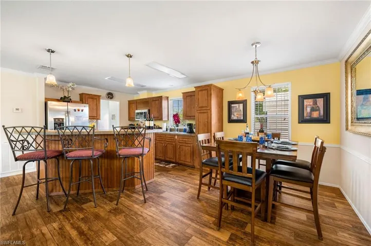 Dining area featuring dark wood-type flooring, ornamental molding, sink, and a chandelier