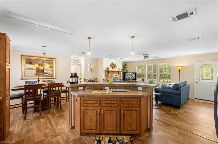 Kitchen featuring a kitchen island, dark wood-type flooring, ceiling fan, and a fireplace