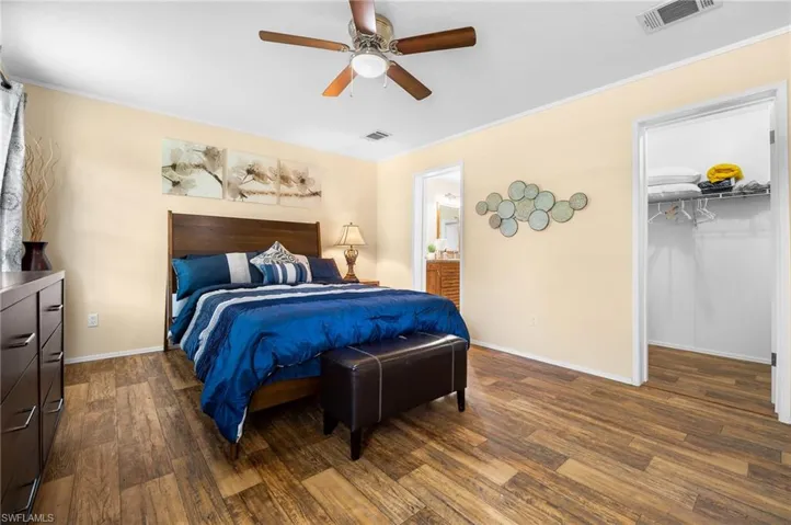 Bedroom with dark wood-type flooring, ceiling fan, a spacious closet, and a closet