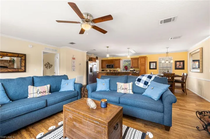 Living room with crown molding, ceiling fan, and light hardwood / wood-style floors