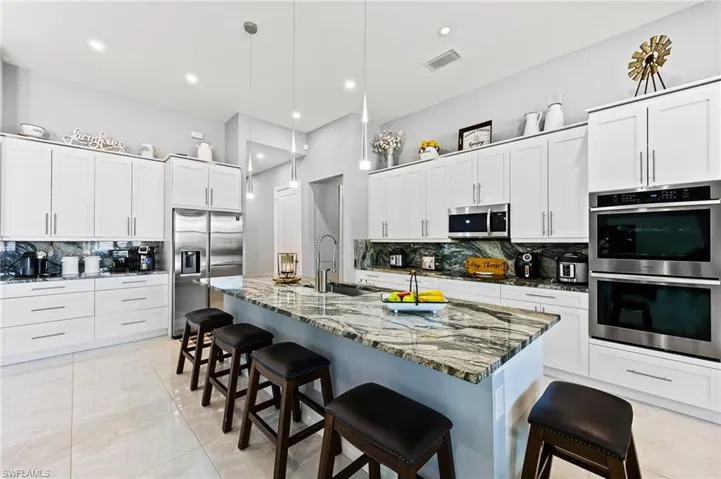 Kitchen with appliances with stainless steel finishes, a kitchen breakfast bar, and backsplash