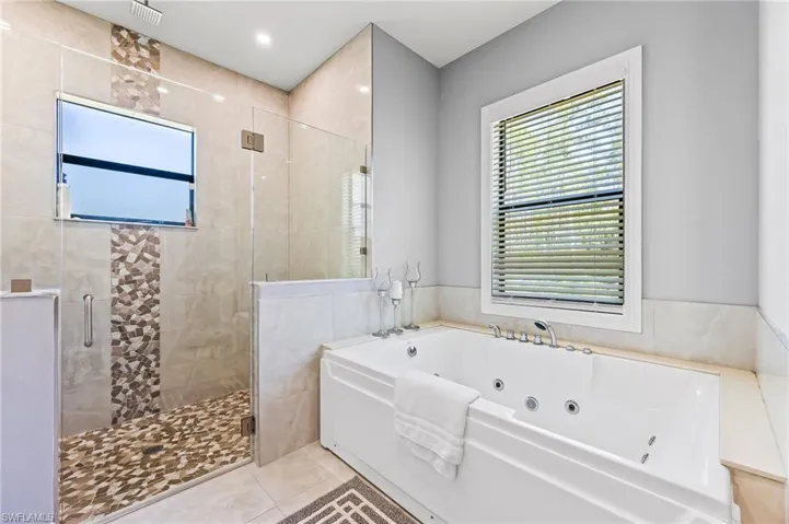 Bathroom featuring tile flooring, tile walls, and plus walk in shower