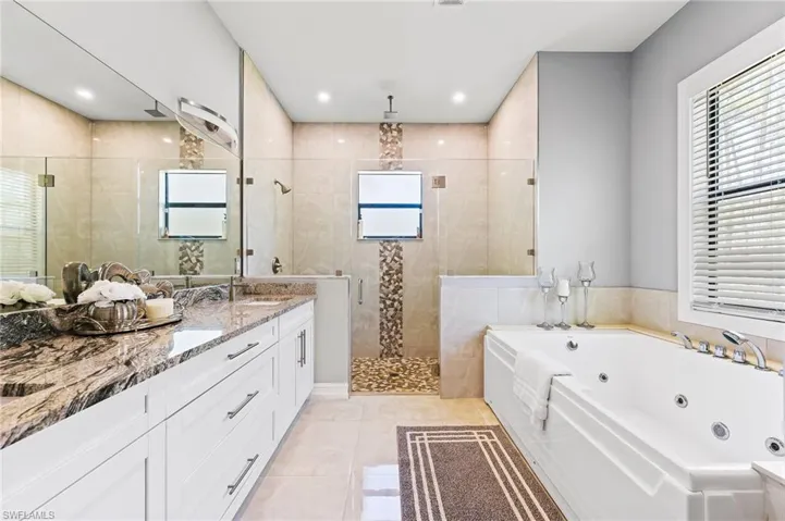 Bathroom featuring tile walls, tile flooring, dual vanity, and separate shower and tub