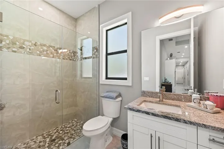 Bathroom with an enclosed shower, oversized vanity, tile flooring, and toilet