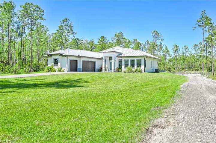 View of front of home featuring a front yard, a garage, and central AC unit