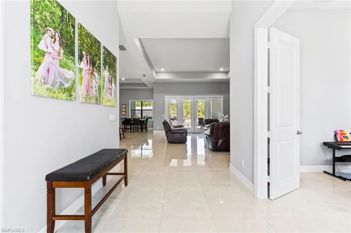 Corridor featuring a tray ceiling, light tile flooring, and french doors