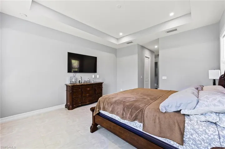 Bedroom featuring a tray ceiling and light tile flooring