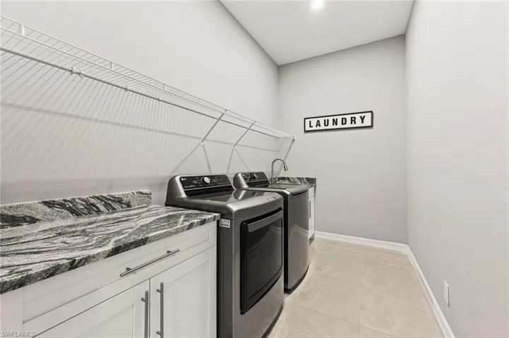 Laundry room with washer and clothes dryer, cabinets, and light tile floors