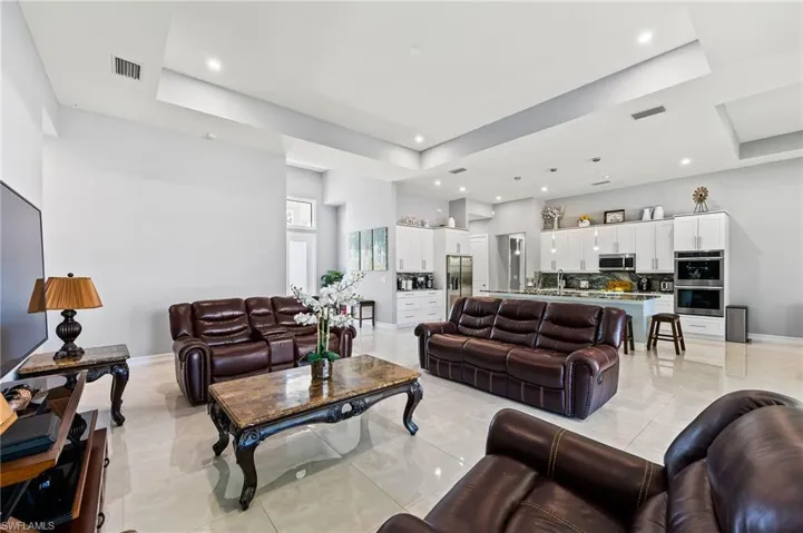 Living room featuring a tray ceiling and light tile floors