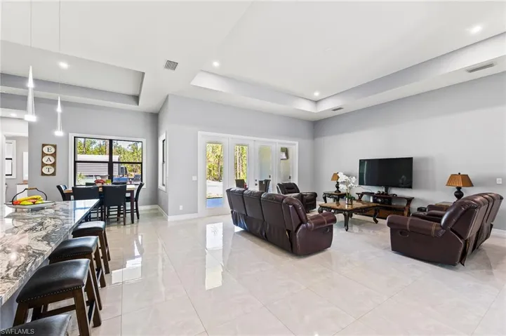 Living room featuring a raised ceiling, french doors, and light tile floors