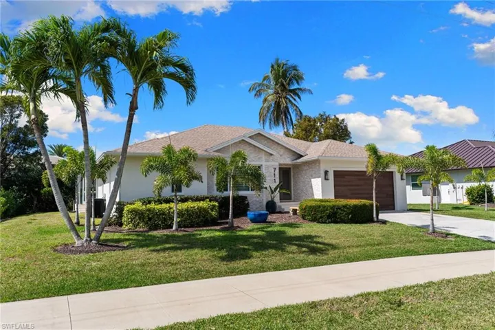 Single story home featuring an attached garage, a front yard, driveway, and roof with shingles