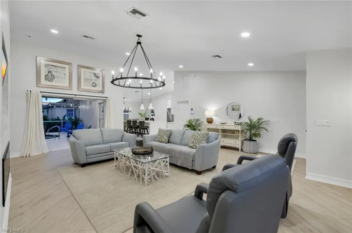 Living area featuring recessed lighting, a chandelier, lofted ceiling, and light wood finished floors