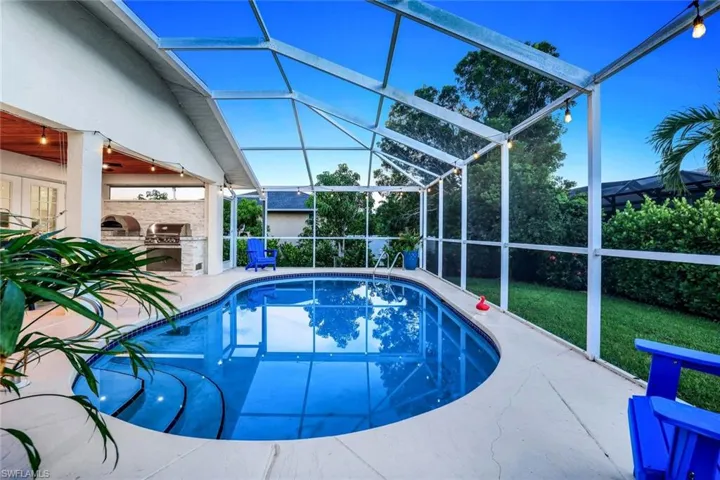 Outdoor pool with area for grilling, a lanai, a patio area, a sunroom, and a yard