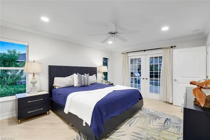 Bedroom featuring french doors, crown molding, light wood-style floors, a ceiling fan, and access to exterior