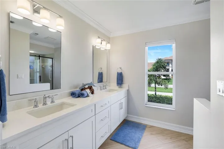 Full bathroom with a stall shower, double vanity, crown molding, and light wood-style flooring