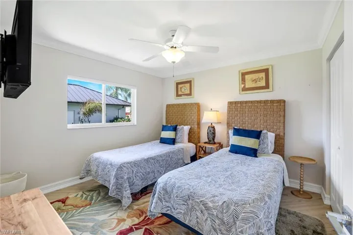 Bedroom with crown molding, a closet, a ceiling fan, and wood finished floors