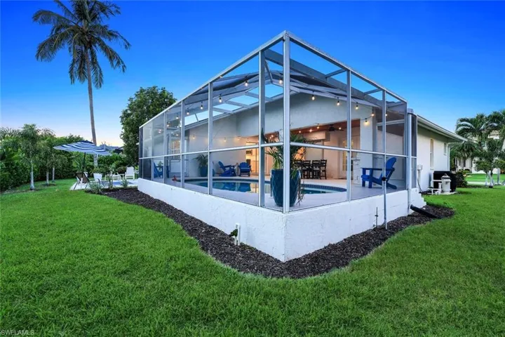 Back of house with an outdoor pool, glass enclosure, a lawn, and a sunroom