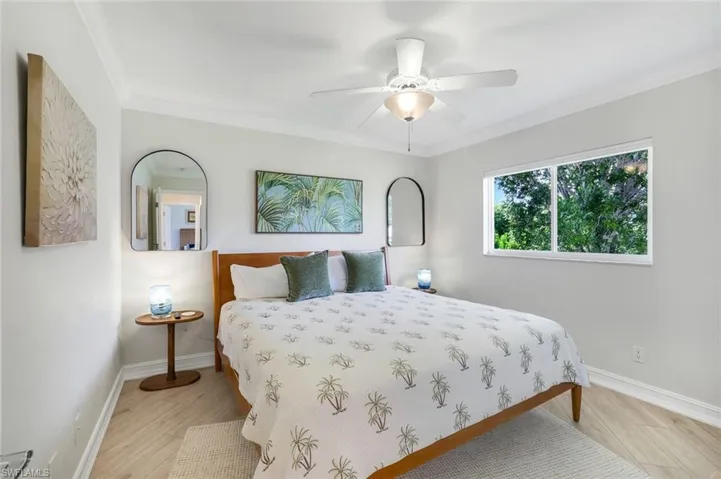 Bedroom with crown molding, a ceiling fan, and light wood-style floors
