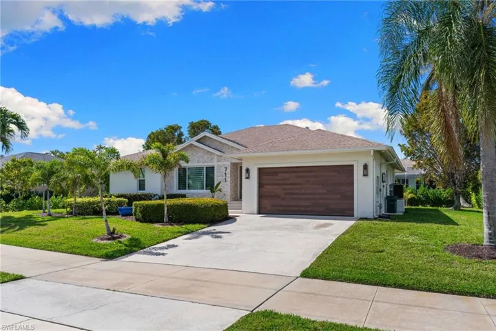 Single story home featuring a front lawn, a garage, concrete driveway, and stucco siding
