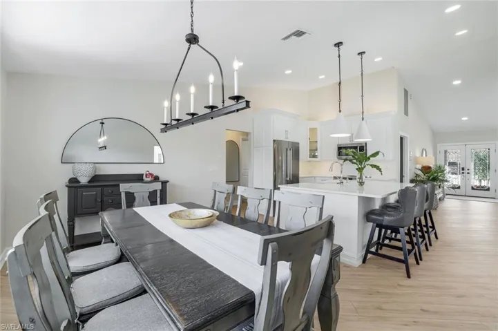 Dining area with french doors, light wood-type flooring, high vaulted ceiling, and recessed lighting