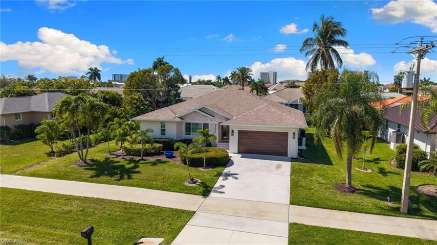 View of front of house featuring a front lawn, driveway, an attached garage, and a residential view