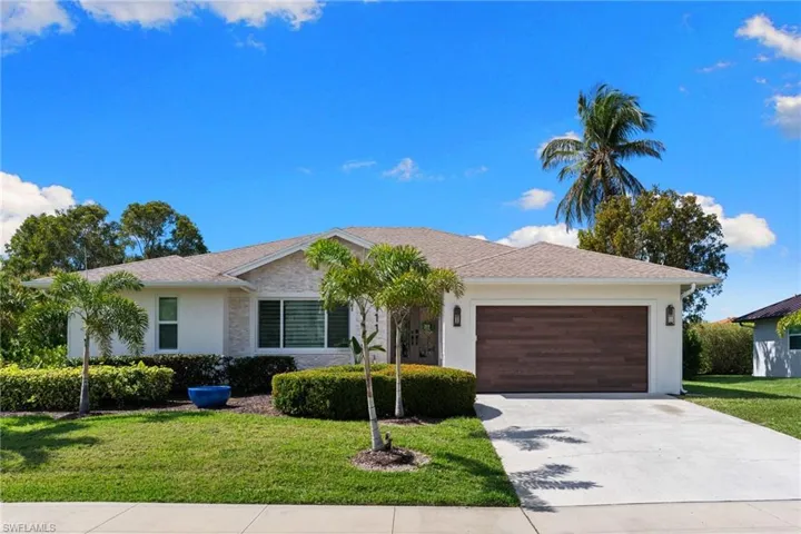Ranch-style home featuring a garage, a front lawn, concrete driveway, and stucco siding