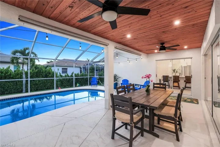 Swimming pool featuring a sunroom, a lanai, outdoor dining space, and a patio area