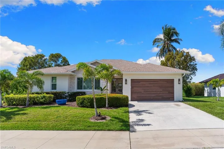 Single story home featuring a front lawn, a garage, driveway, and stucco siding