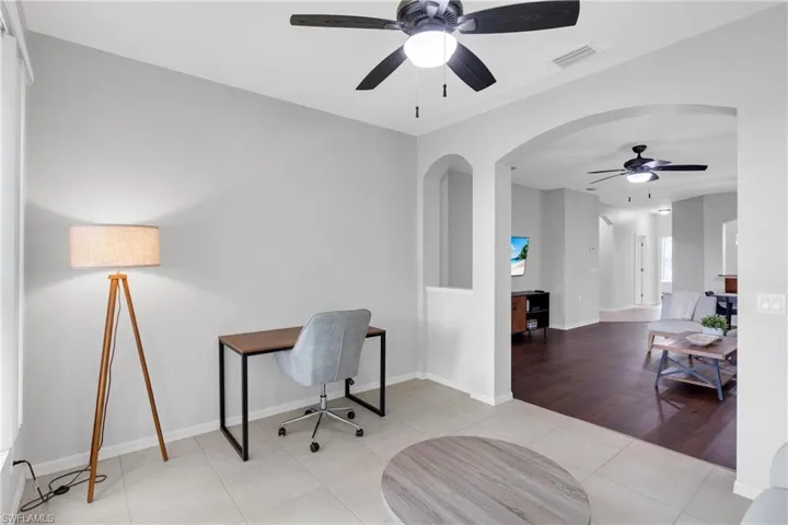 Recessed wall niches, arched doorways, tiled flooring, wood-finish flooring, and ceiling fans with integrated lighting