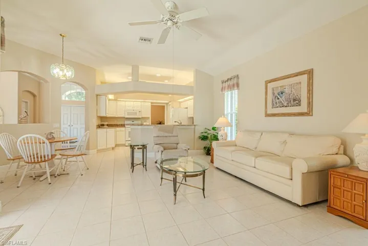 Tiled living room with ceiling fan with notable chandelier