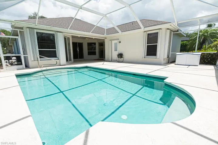 View of pool featuring a patio and glass enclosure