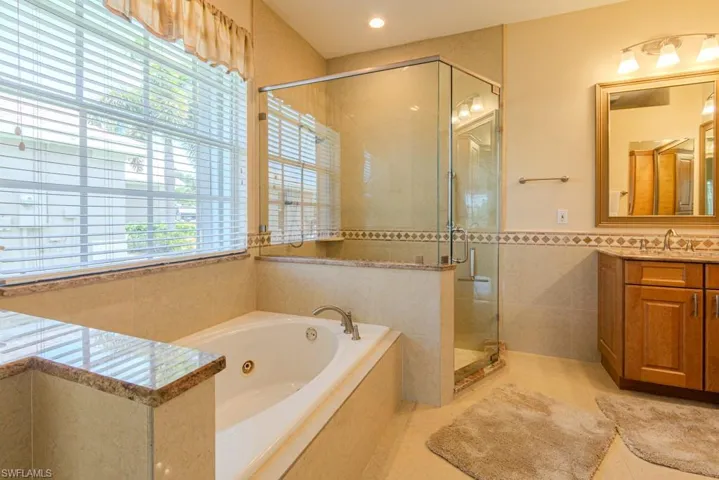 Bathroom with tile flooring, plenty of natural light, shower with separate bathtub, and oversized dual vanity