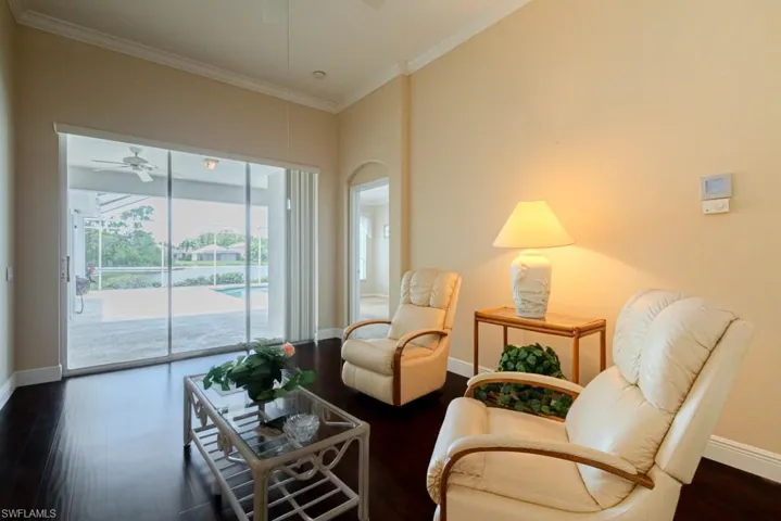 Living room featuring dark hardwood / wood-style floors, ceiling fan, and crown molding