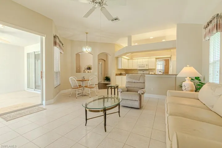 Living room with light tile floors and ceiling fan with notable chandelier