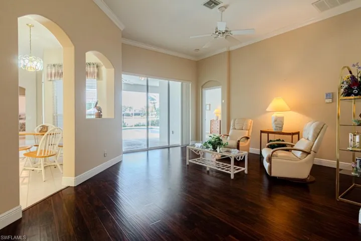 Sitting room featuring tile floors, ceiling fan with notable chandelier, and crown molding