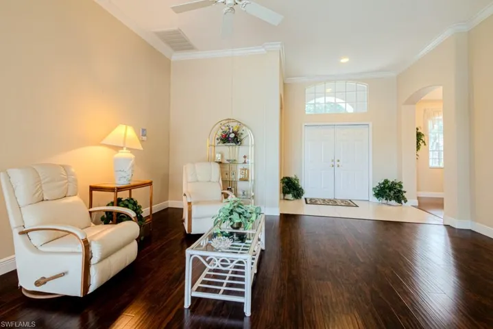 Living room with ceiling fan, dark tile floors, and ornamental molding