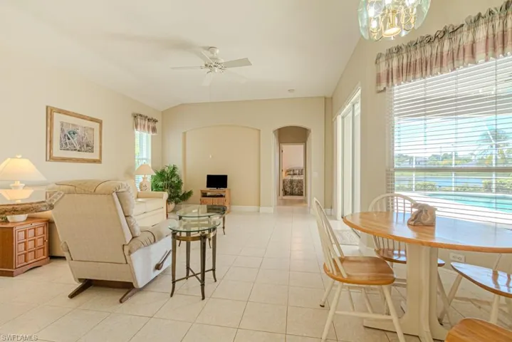 Living room featuring light tile flooring and ceiling fan with notable chandelier