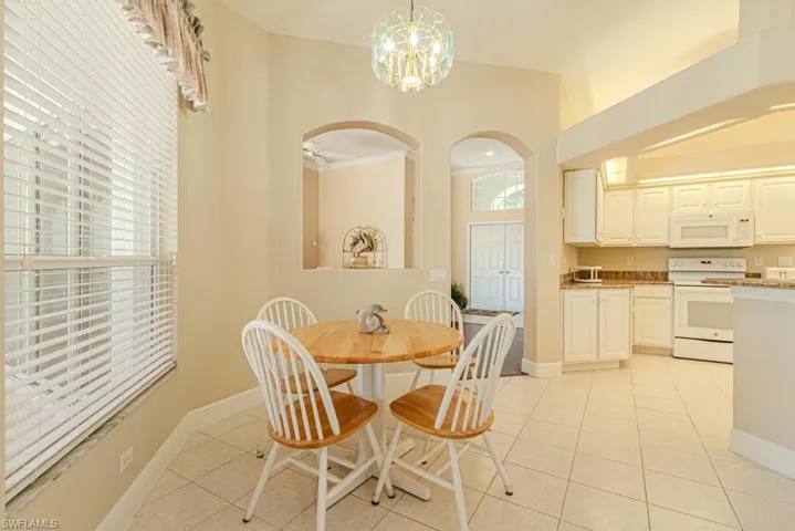 Dining space with ceiling fan with notable chandelier, light tile floors, and crown molding