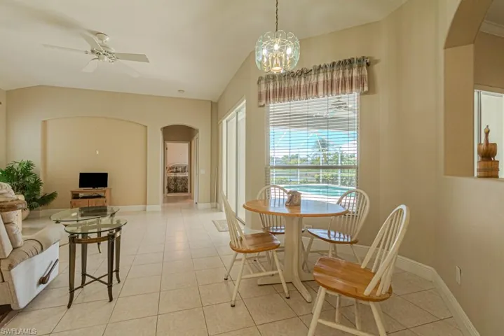 Tiled dining area featuring ceiling fan with notable chandelier