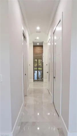 Corridor with marble finish floor, baseboards, and crown molding
